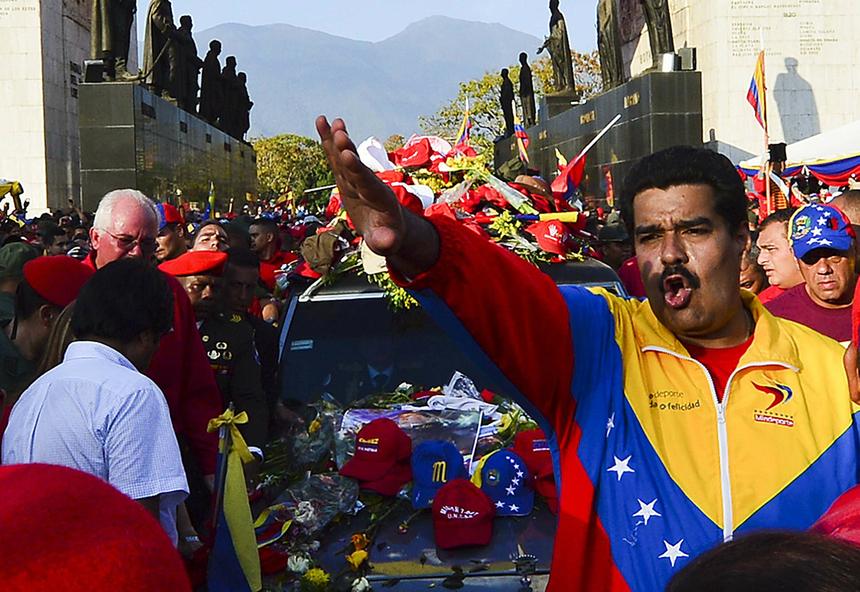 Николас Мадуро (справа) жестикулирует, сопровождая похоронный кортеж покойного президента Венесуэлы Уго Чавеса по прибытии в Военную академию 6 марта 2013 года